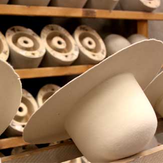 Tan colored hats on a manufacturing line getting prepared for steaming