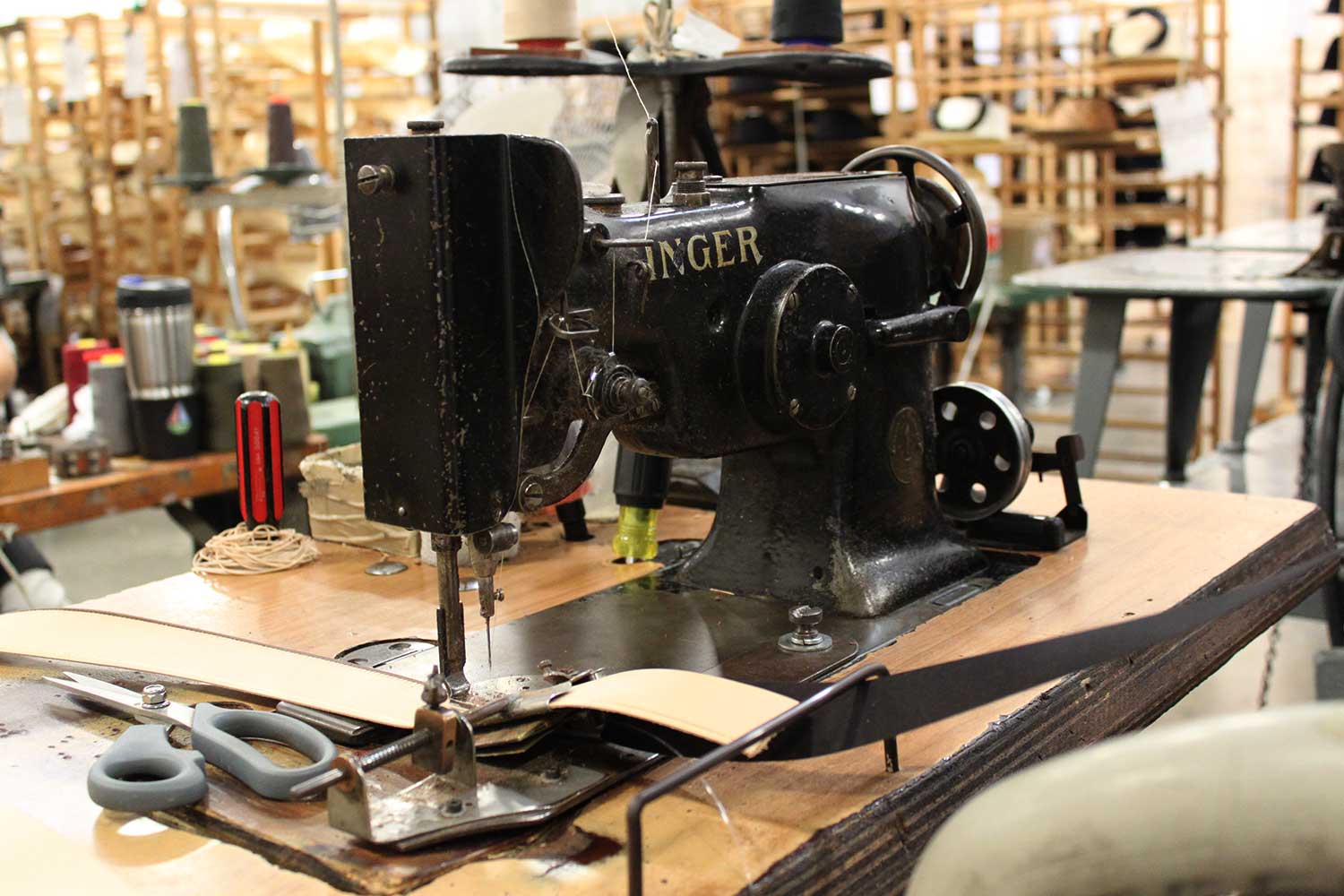 A very old black Singer sewing machine resting on a wooden table