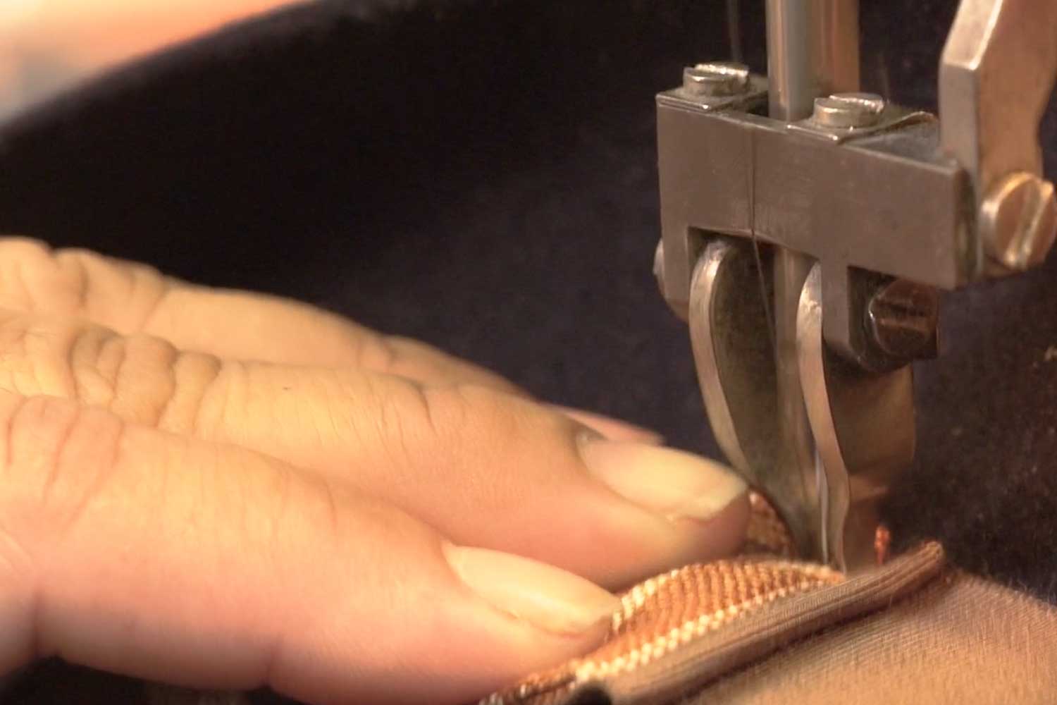 Close up of a hand sewing onto a black hat